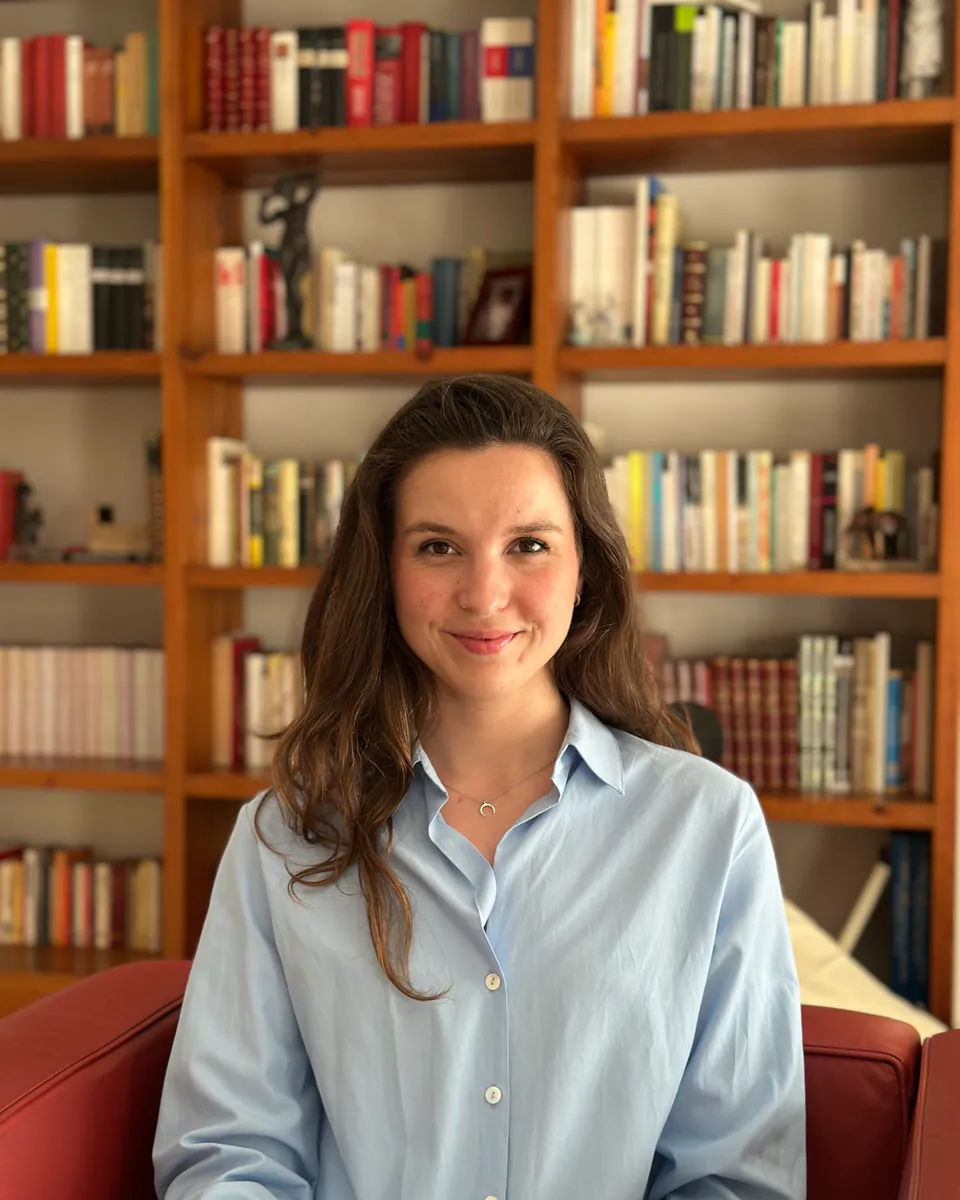 Marta Gimeno, psicóloga, sentada frente a una librería